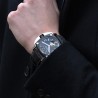 Montre Humbert Droz portée sur bras d'un homme en costume noir.